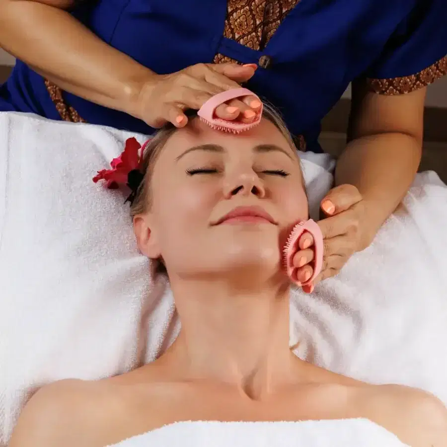 Client resting with a cleansing mask and warm towels during a facial